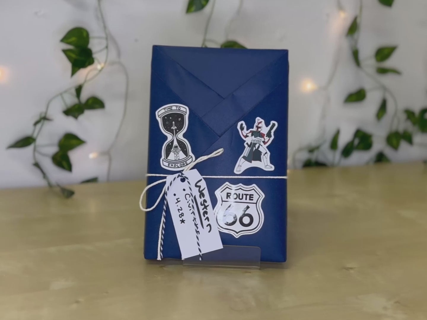 A woman inserting the accessories included with the blind date with a book for men. The book has blue wrapping, a tag noting the Western genre, and three stickers on the front of the wrapping.